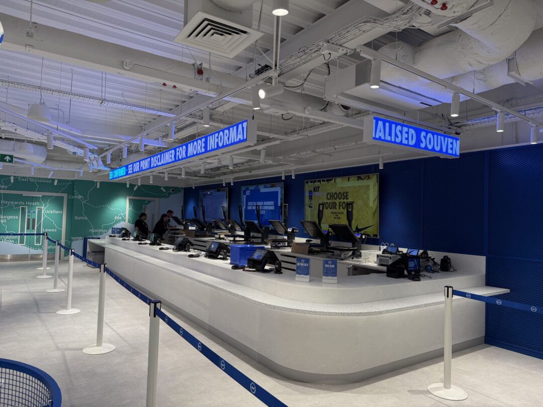 Retail environment showing large digital screens and LED tickers.